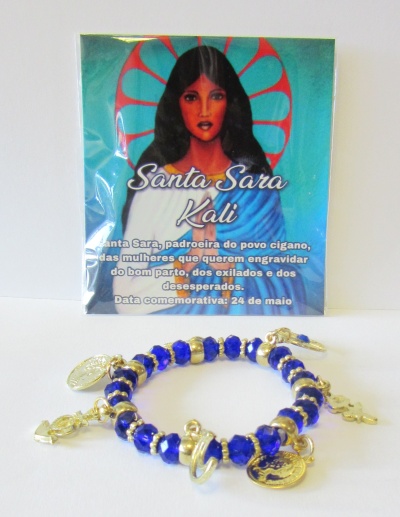 Pulseira azul e dourada com pendentes e imagem de Santa Sara Kali no fundo