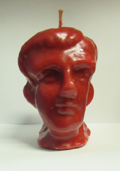 Vela vermelha em forma de cabeça humana sobre superfície branca