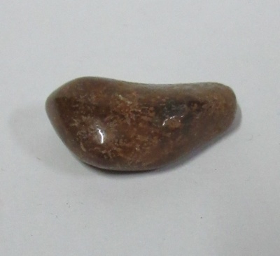 pedra polida castanha com brilho e padrões claros sobre fundo branco