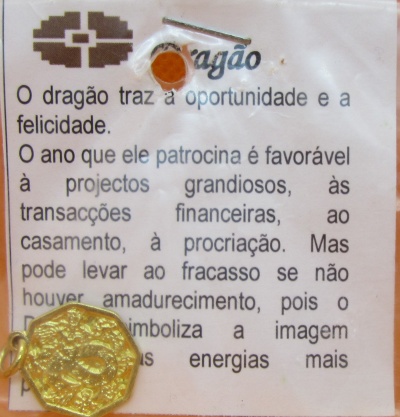 Etiqueta com texto em português e amuleto dourado em forma de moeda