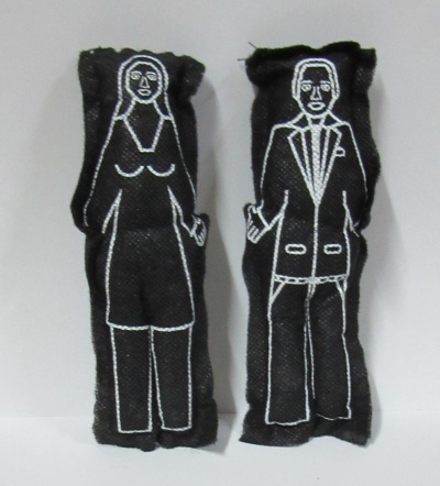 Duas almofadas de tecido preto com desenhos brancos de uma mulher e um homem