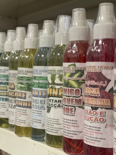 Frascos spray coloridos em prateleira branca com rótulos em português