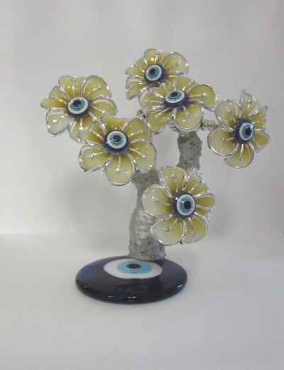 Escultura de flores amarelas com olhos decorativos em base redonda preta.