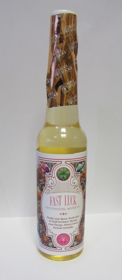 Garrafas com líquido amarelo e rótulo decorado 'FAST LUCK CLEANSING WATER' e papel dourado 'SOUL STICKS'