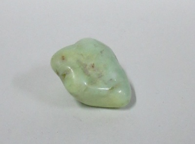 Pedra verde clara polida com manchas castanhas sobre fundo branco