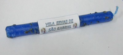 Vela azul decorativa com folhas secas e rótulo 'VELA ERVAS DE SÃO GABRIEL'