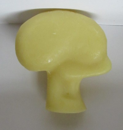 Sabonete amarelo em forma de cogumelo sobre superfície branca.