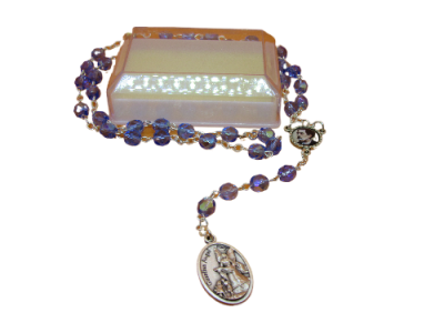 Terço com contas roxas e medalha religiosa sobre base translúcida