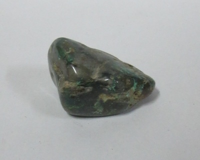 pedra polida verde e cinza sobre superfície branca