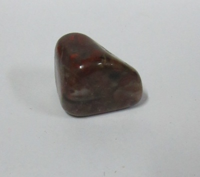 pedra polida castanho escura com manchas pretas e vermelhas sobre fundo branco