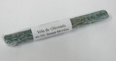 Vela de oferenda verde com etiqueta e embalagem em plástico sobre fundo branco