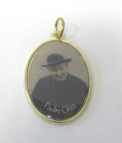 Medalha oval dourada com imagem de um homem e texto Padre Cruz