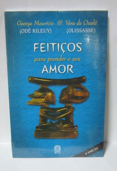 Capa de livro azul com título 'Feitiços para prender o seu amor' e imagem de estatueta dourada