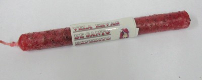 Vela vermelha rugosa com rótulo branco e texto em espanhol, sobre fundo branco.