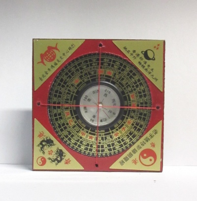 Quadro em madeira com compasso circular decorado em vermelho, amarelo e preto com caracteres chineses