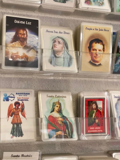 Cartões religiosos com imagens de santos e textos em português em suportes transparentes