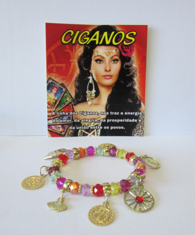 Bracelete colorido com pendentes metálicos dourados e cartão com imagem de mulher e texto CIGANOS no fundo