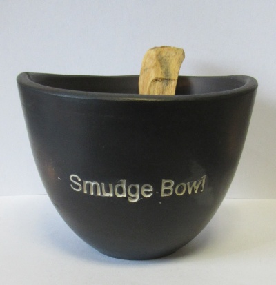 Recipiente preto com inscrição 'Smudge Bowl' e pedaço de madeira dentro
