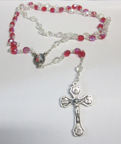 Rosário com contas vermelhas e transparentes, crucifixo metálico e medalha oval com imagem religiosa