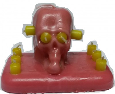 Vela decorativa em forma de caveira cor-de-rosa com detalhes amarelos e base retangular cor-de-rosa com velas pequenas amarelas