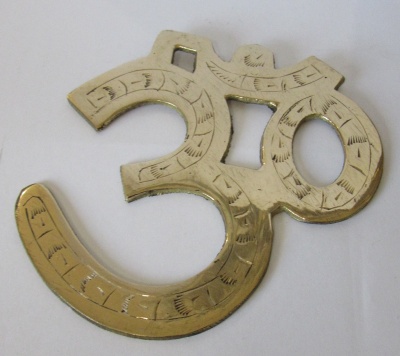 Objeto decorativo metálico dourado em formato do símbolo Om