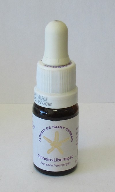 Frasco pequeno com conta-gotas branco e etiqueta branca com texto e símbolo dourado.