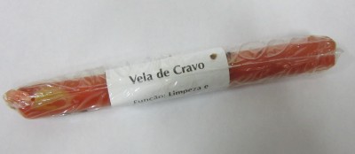 Vela vermelha em plástico com etiqueta branca que diz Vela de Cravo