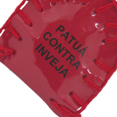 Produto artesanal em couro vermelho com texto preto 'PATUÁ CONTRA INVEJA'