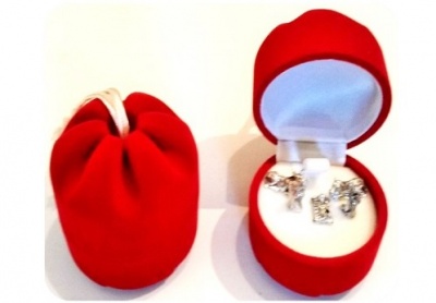 Caixa de veludo vermelha em formato de maçã com joias prateadas dentro