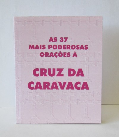 Livro rosa claro com texto 'AS 37 MAIS PODEROSAS ORAÇÕES À CRUZ DA CARAVACA'