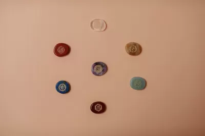 Pedras coloridas ovais e uma anilha transparente sobre fundo cor de salmão