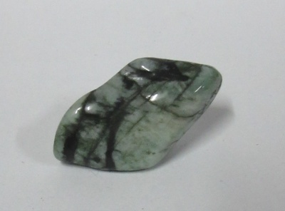 Pedra polida verde com veios pretos sobre superfície branca