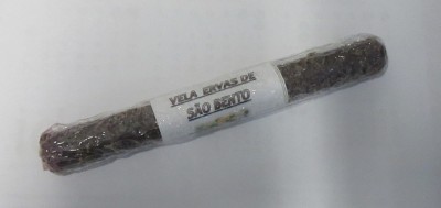 Vela preta enrolada em plástico com etiqueta branca sobre superfície branca