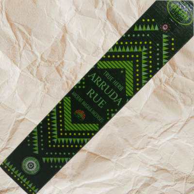 Embalagem preta de incenso com padrões verdes e texto sobre papel amassado claro