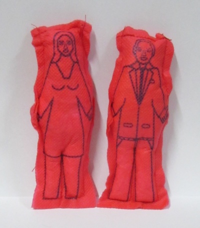 Dois bonecos de tecido vermelho com desenhos a preto representando uma mulher e um homem