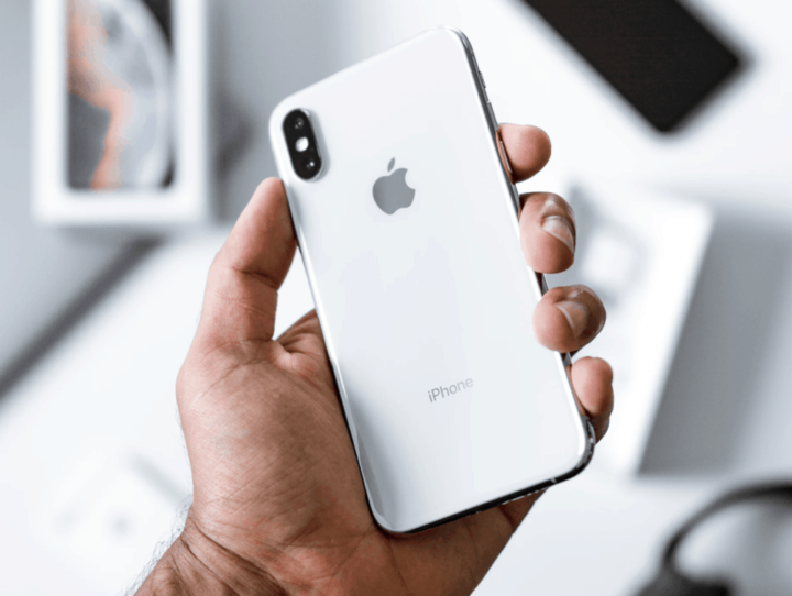 Telemóvel Apple iPhone branco com dois sensores de câmara traseira na mão