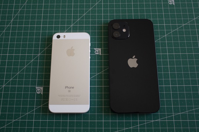 Dois iPhones, um branco e ouro rosa e outro preto, sobre uma superfície verde com grelha