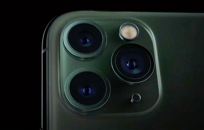 Detalhe da parte traseira de telemóvel verde com três câmaras e flash