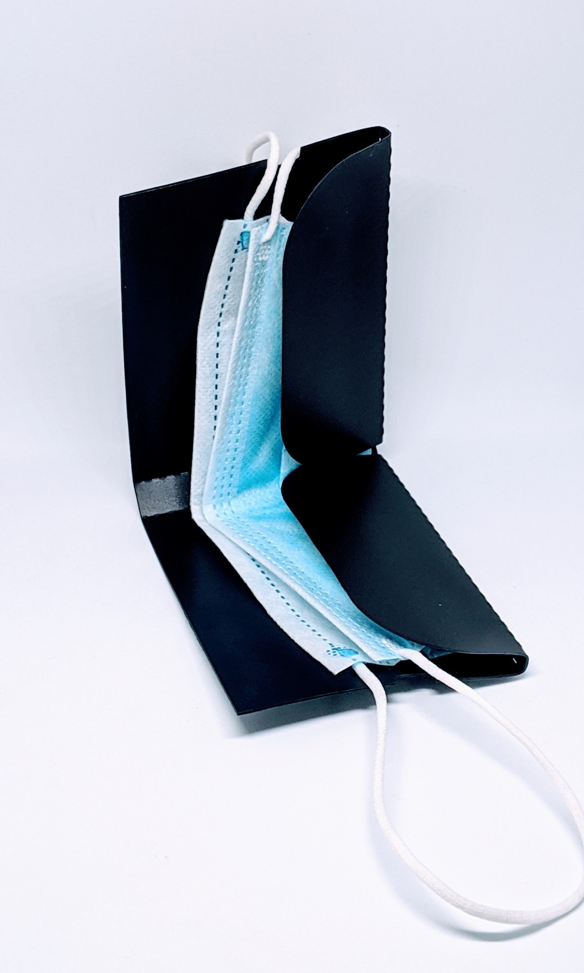 Estojo preto rígido aberto com máscara facial azul dentro