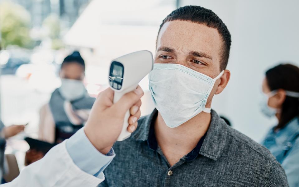 Homem com máscara a ter temperatura medida com termómetro digital.