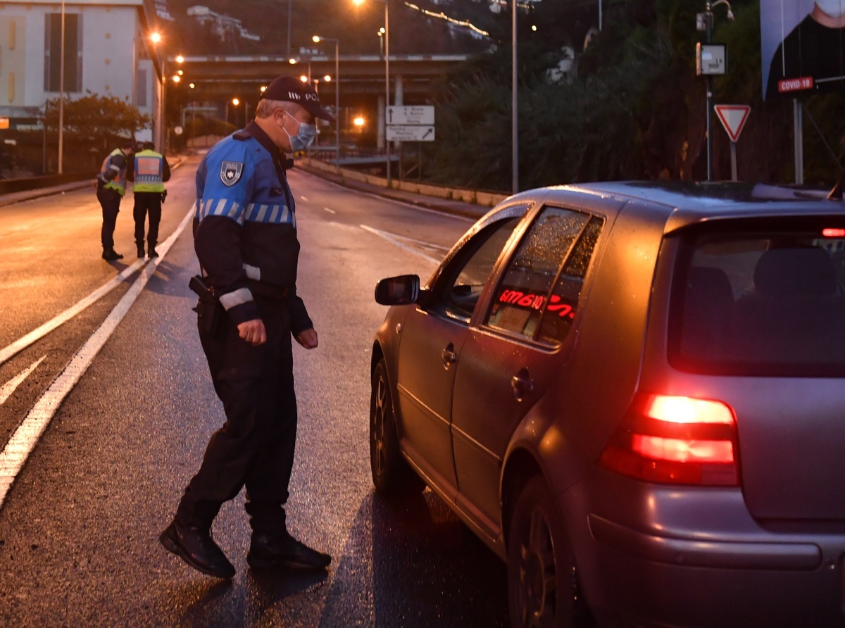 Polícia a verificar um carro parado numa estrada ao entardecer.