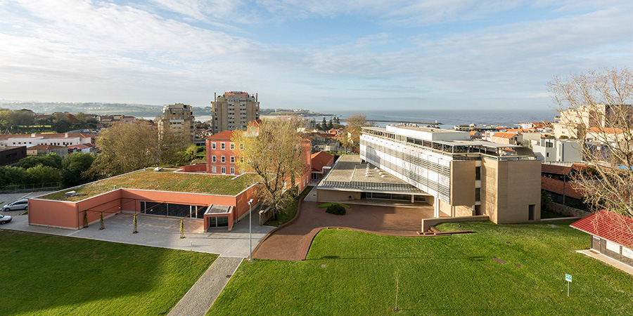 Conjunto de edifícios institucionais com áreas verdes e vista para a cidade e o mar