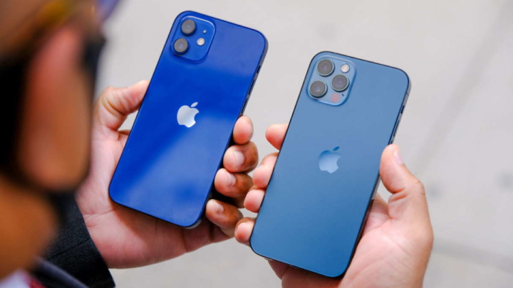Dois iPhones azuis segurados por uma pessoa, um com câmara dupla e outro com câmara tripla