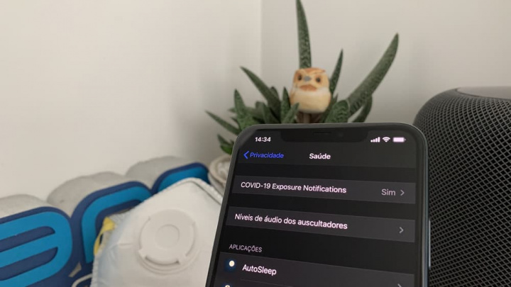 Smartphone com ecrã de definições de saúde em português com planta e objetos ao fundo