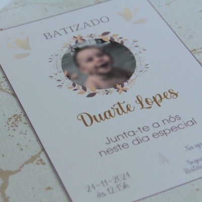 Convite de batizado branco com texto a preto e dourado e fotografia oval