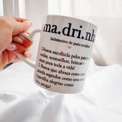Caneca branca com texto em português sobre madrinha segurada à mão em fundo branco