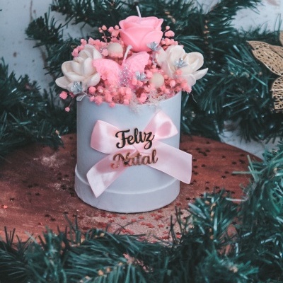 Vela decorativa branca com flores e laço cor-de-rosa com texto Feliz Natal