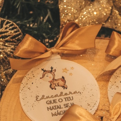 Anel decorativo redondo branco com desenho de veado e estrelas, texto em português, fita dourada, decoração natalícia