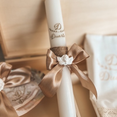 Vela branca com laço castanho e concha em caixa de madeira