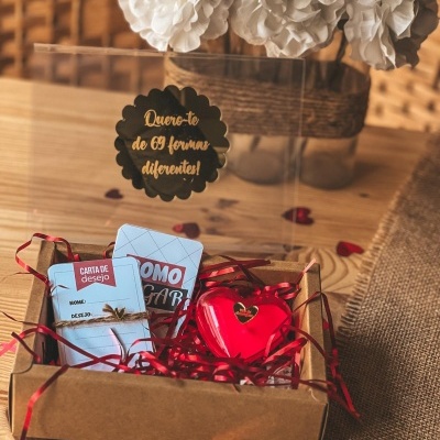 Caixa de presente com cartão, coração vermelho e flores brancas ao fundo